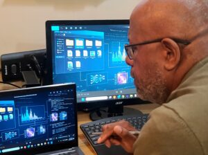 Voice actor listening to AI-generated voice samples on a laptop in his studio